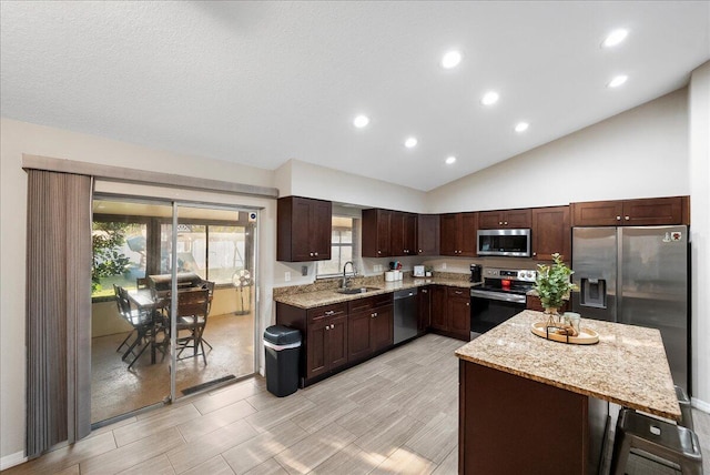 kitchen with sink, high vaulted ceiling, dark brown cabinets, stainless steel appliances, and light stone countertops