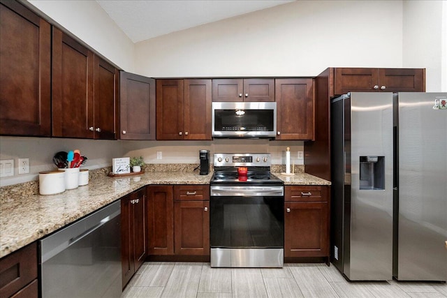 kitchen with light stone counters, lofted ceiling, and appliances with stainless steel finishes