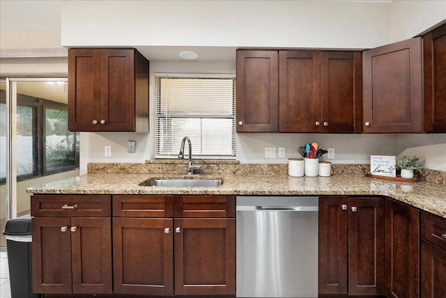 kitchen with stainless steel dishwasher, light stone countertops, and sink