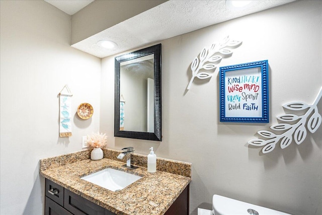 bathroom featuring vanity, a textured ceiling, and toilet