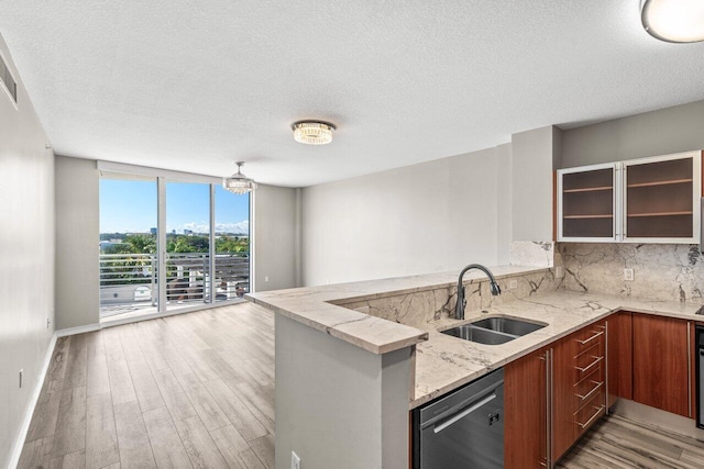 kitchen featuring decorative backsplash, dishwasher, a peninsula, a wall of windows, and a sink