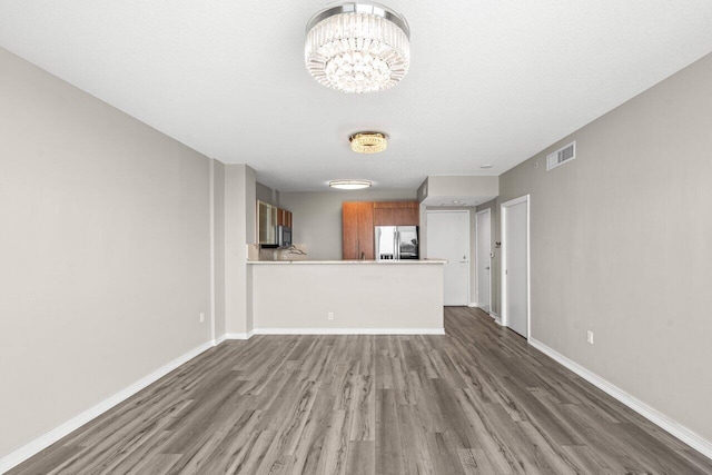 unfurnished living room with hardwood / wood-style flooring, a textured ceiling, and a notable chandelier