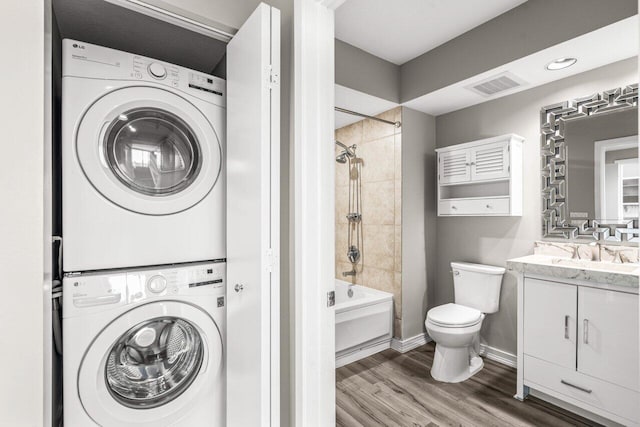 laundry area with sink, hardwood / wood-style flooring, and stacked washer / dryer