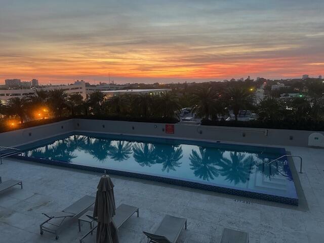 pool at dusk featuring a patio