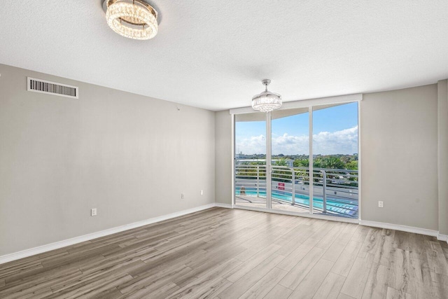 empty room with hardwood / wood-style flooring, a textured ceiling, and a chandelier