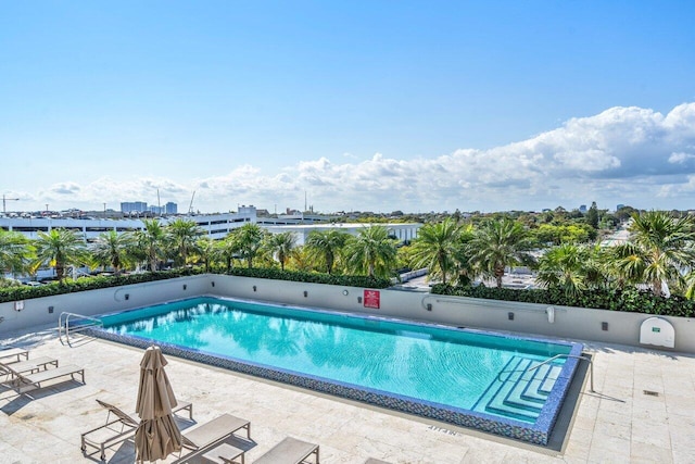 community pool with a view of city and a patio