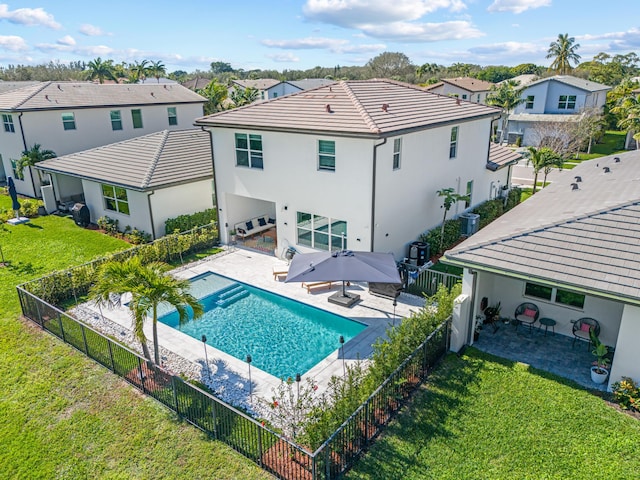 rear view of house with a fenced in pool, a yard, and a patio area