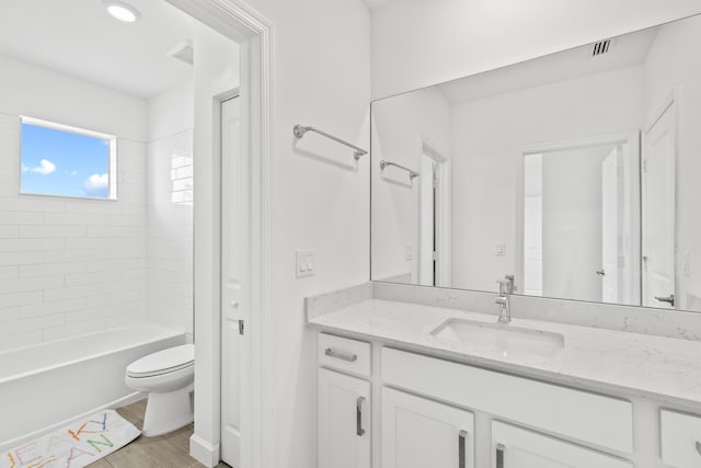 full bathroom with vanity, tiled shower / bath combo, toilet, and hardwood / wood-style flooring