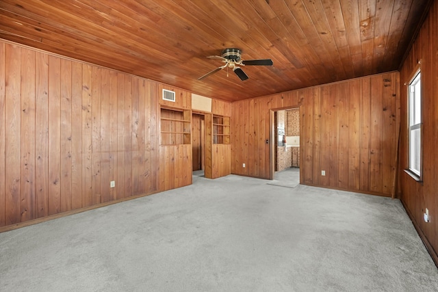 spare room featuring light carpet, wood ceiling, wooden walls, and ceiling fan