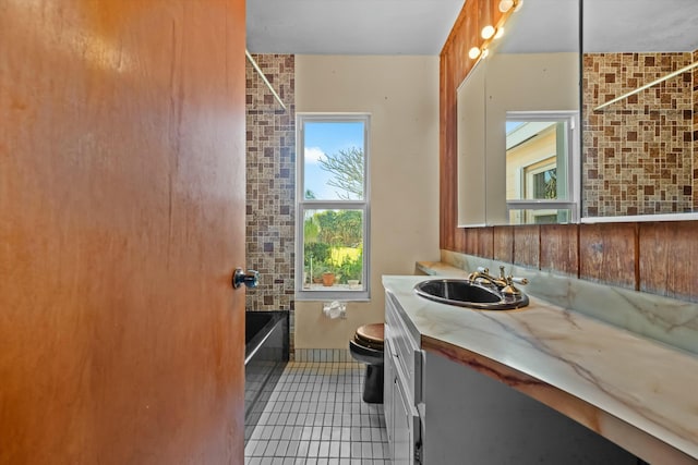 full bathroom with tub / shower combination, vanity, brick wall, tile patterned floors, and toilet