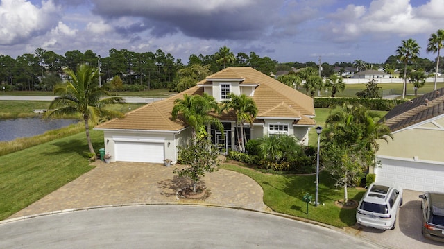 view of front facade featuring stucco siding, decorative driveway, an attached garage, a front yard, and a tiled roof