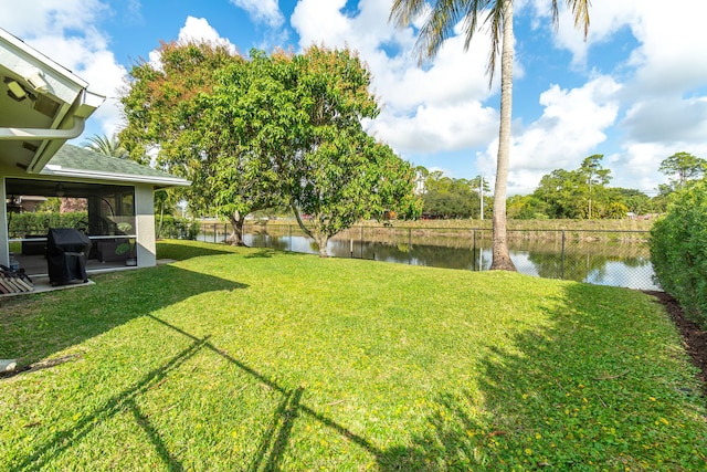 view of yard with a sunroom and a water view