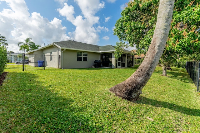 rear view of property featuring a yard and a sunroom