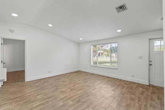 spare room featuring vaulted ceiling and light hardwood / wood-style floors