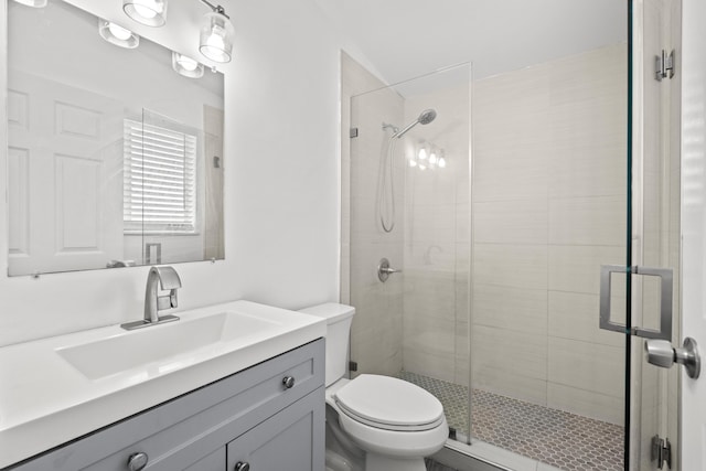 bathroom featuring a shower with door, vanity, and toilet