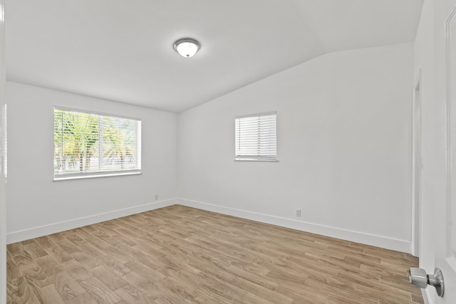 empty room featuring vaulted ceiling and light wood-type flooring