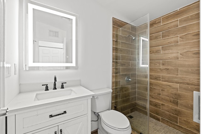 bathroom with vanity, toilet, and a tile shower