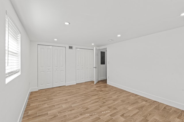 unfurnished bedroom with multiple closets and light hardwood / wood-style flooring