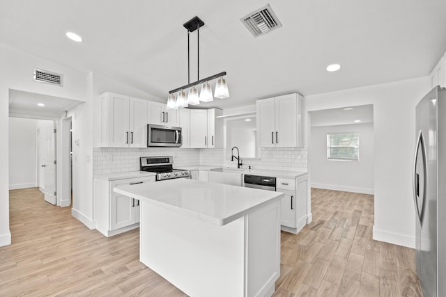 kitchen featuring sink, a center island, appliances with stainless steel finishes, light hardwood / wood-style floors, and white cabinets