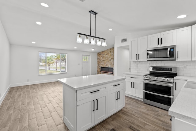 kitchen featuring tasteful backsplash, decorative light fixtures, light hardwood / wood-style flooring, stainless steel appliances, and white cabinets