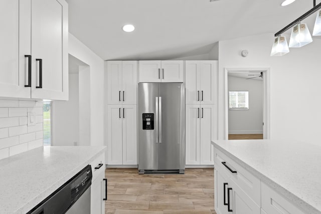 kitchen with appliances with stainless steel finishes, decorative light fixtures, light stone countertops, and white cabinets