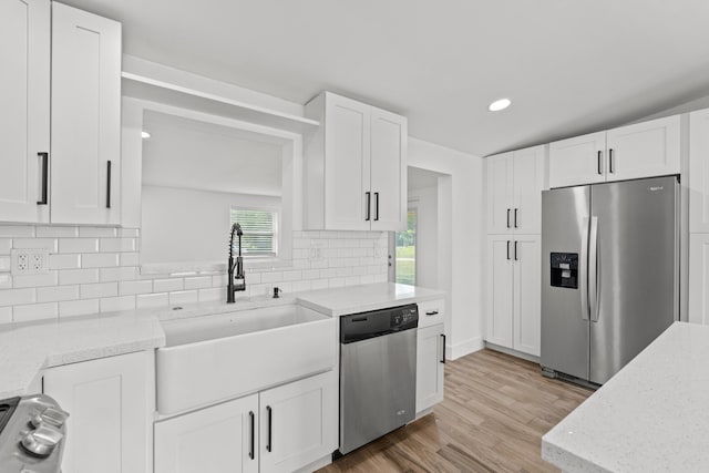 kitchen featuring sink, appliances with stainless steel finishes, tasteful backsplash, light stone countertops, and white cabinets