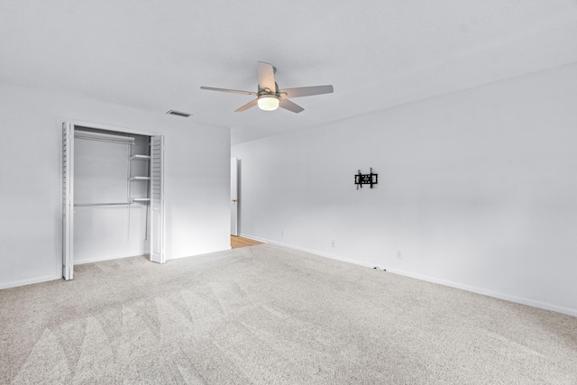 unfurnished bedroom featuring light colored carpet, ceiling fan, and a closet