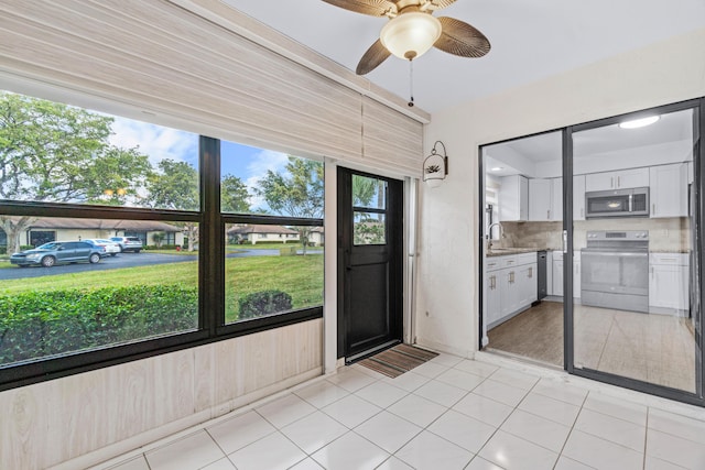 unfurnished sunroom with ceiling fan, plenty of natural light, and sink