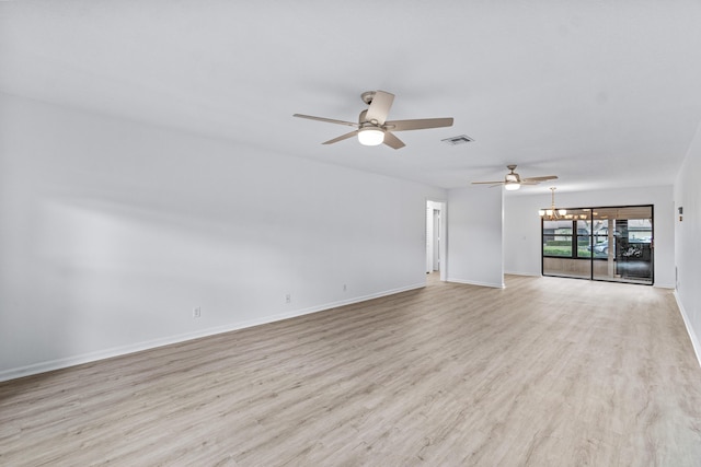 empty room with ceiling fan with notable chandelier and light wood-type flooring