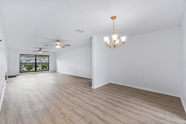 spare room with an inviting chandelier and light hardwood / wood-style floors