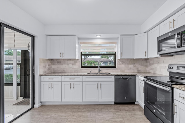 kitchen featuring sink, light stone counters, a wealth of natural light, stainless steel appliances, and white cabinets