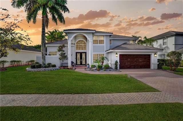 mediterranean / spanish-style house with a garage, a yard, and french doors