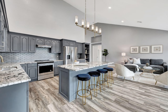 kitchen with sink, gray cabinetry, stainless steel appliances, a center island, and light stone countertops