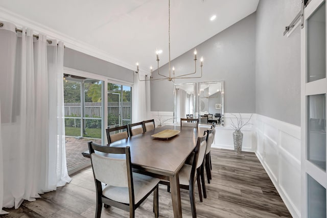 dining area with high vaulted ceiling, hardwood / wood-style flooring, a notable chandelier, crown molding, and a barn door