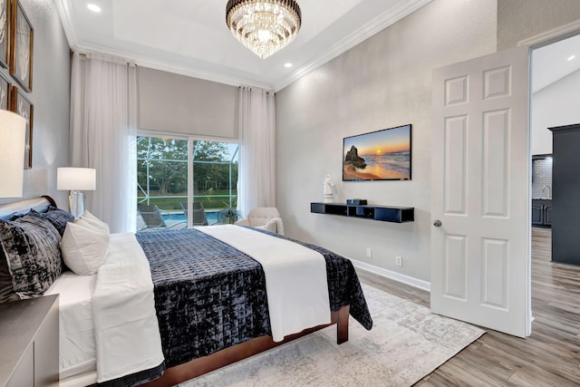 bedroom featuring ornamental molding, a tray ceiling, a chandelier, and light hardwood / wood-style flooring