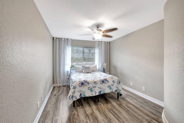 bedroom featuring hardwood / wood-style flooring, a textured ceiling, and ceiling fan