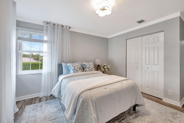 bedroom with ornamental molding, hardwood / wood-style floors, and a closet