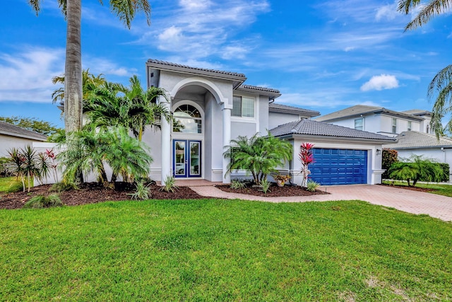 mediterranean / spanish house with a garage and a front lawn