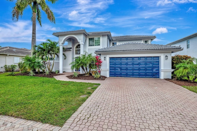 mediterranean / spanish home featuring a garage and a front yard