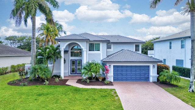 mediterranean / spanish house with a garage and a front lawn