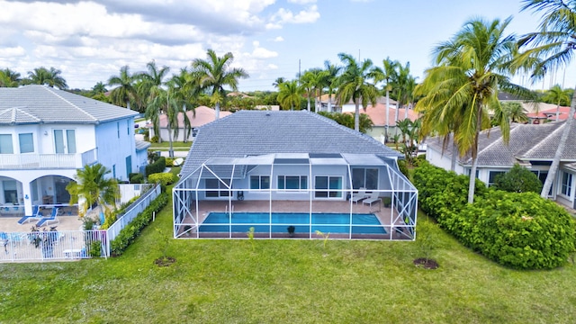 rear view of house featuring a yard, a fenced in pool, and glass enclosure