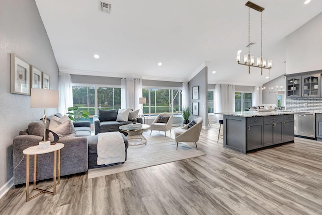 living room with an inviting chandelier, ornamental molding, light hardwood / wood-style floors, and a wealth of natural light