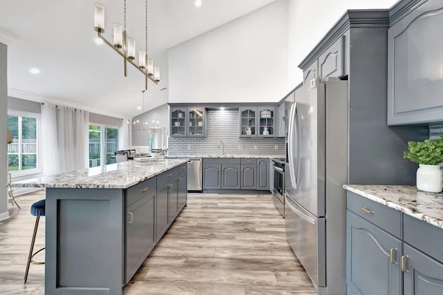 kitchen featuring appliances with stainless steel finishes, gray cabinets, hanging light fixtures, and a kitchen island