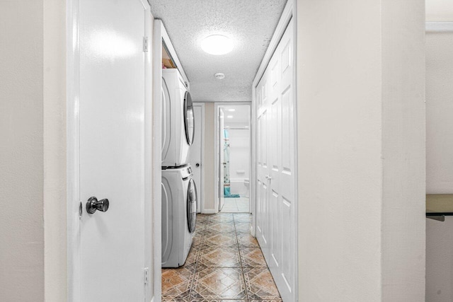 clothes washing area with stacked washer / drying machine and a textured ceiling