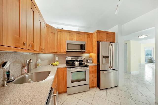 kitchen featuring appliances with stainless steel finishes, sink, decorative backsplash, light tile patterned floors, and light stone countertops