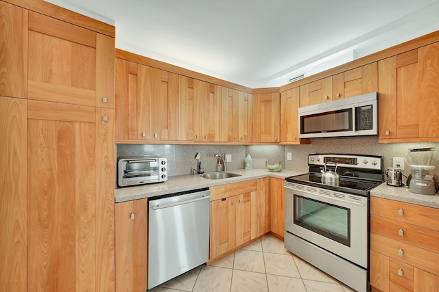 kitchen with tasteful backsplash, stainless steel appliances, sink, and light tile patterned floors