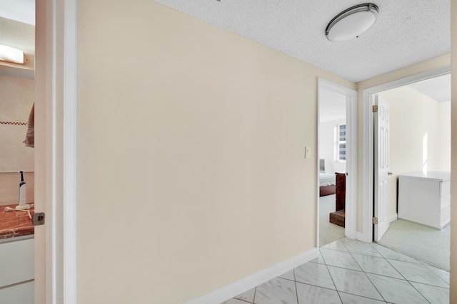 hall featuring light tile patterned floors and a textured ceiling