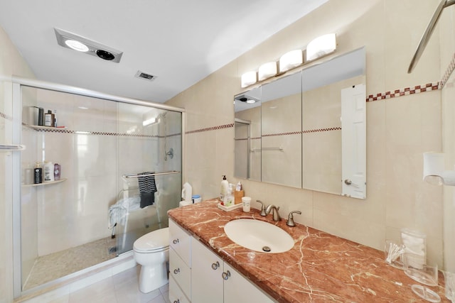 bathroom featuring a shower with door, vanity, tile walls, and toilet