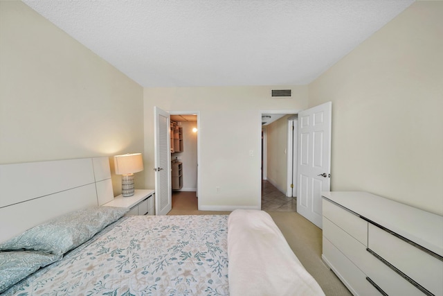 bedroom featuring a spacious closet, light colored carpet, and a textured ceiling