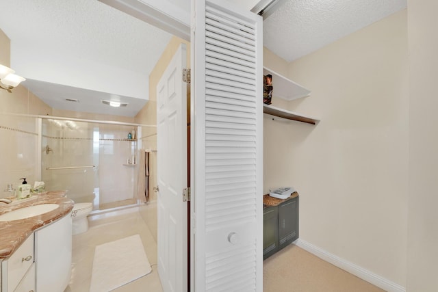 bathroom with a shower with door, tile patterned flooring, vanity, a textured ceiling, and toilet